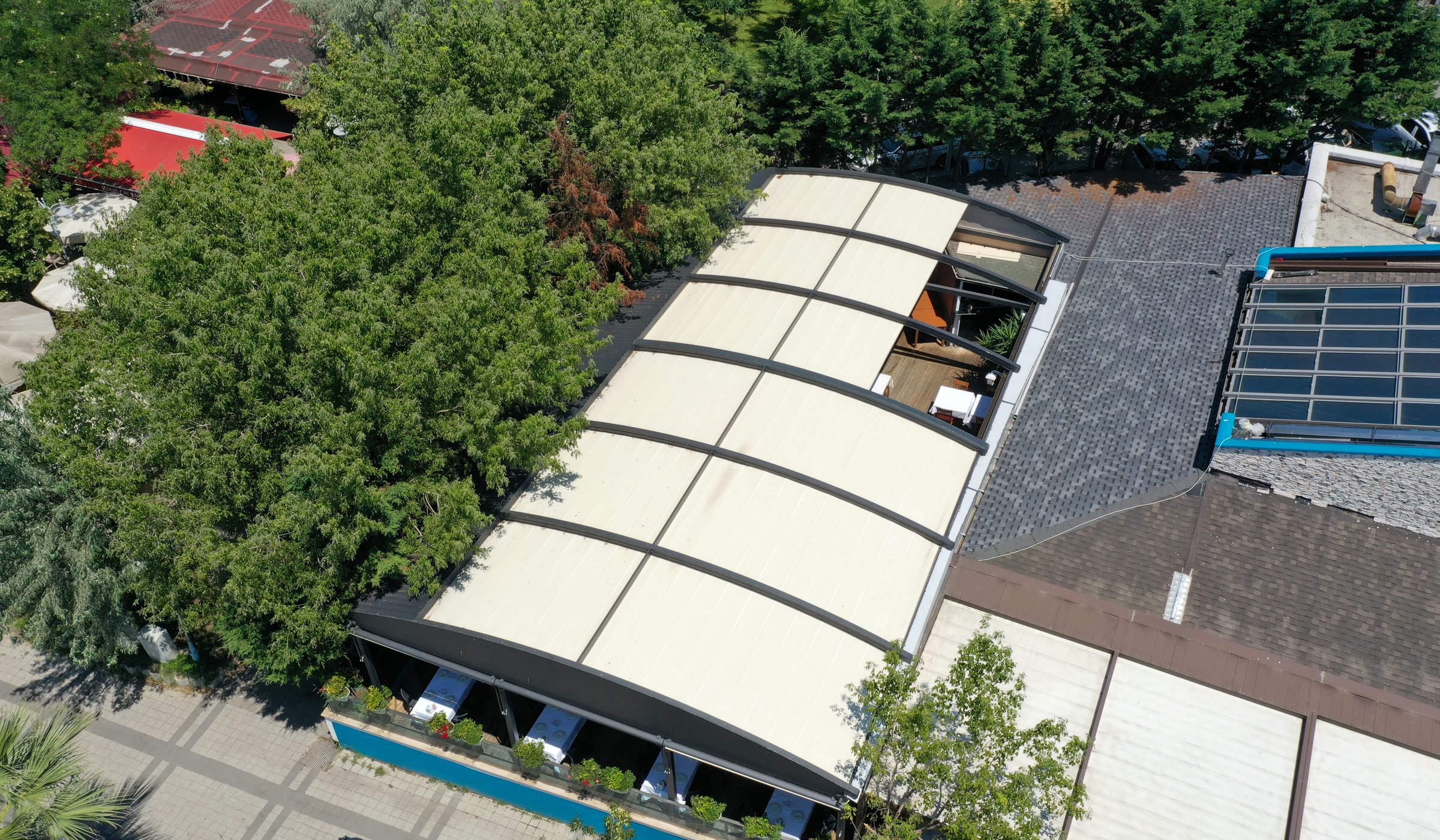 Aerial view of a restaurant terrace covered by an automatic fabric roof pergola